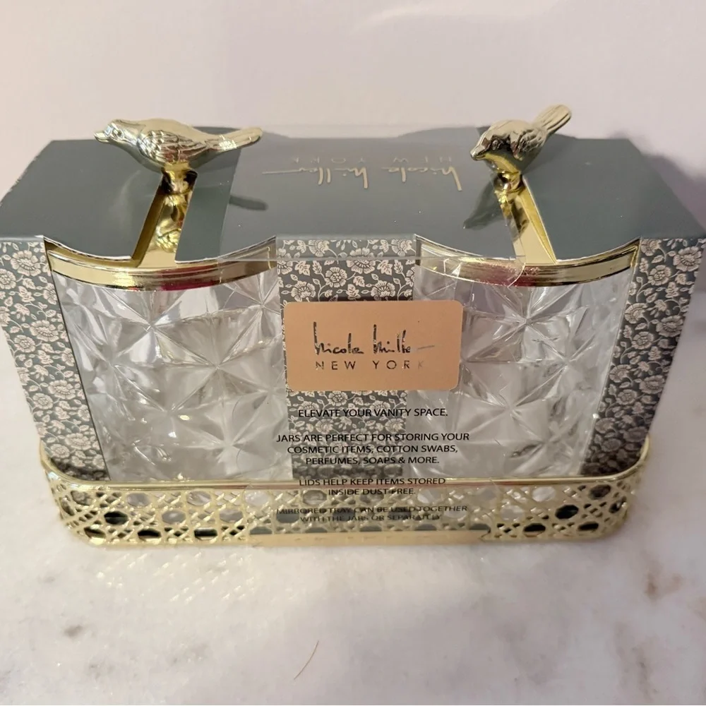 two-piece glass storage jar set with a gold bird lid and decorative tray.